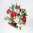 A hand-tied bouquet captured in soft natural light, filled with velvety red roses and vivid pink-red carnations, is cradled by a cloud of small white daisies and fluffy chrysanthemum heads. The roses sit proudly at the centre, their deep crimson petals unfurling in perfect spirals, while the carnations ripple outward with ruffled, almost feathery edges that catch the light. Between them, tiny stars of gypsophila scatter like gentle confetti, adding a dreamy softness to the arrangement. Cool eucalyptus stems arc through the bouquet, their silvery green leaves and rounded shapes giving a fresh, contemporary edge, alongside glossy tropical foliage that grounds the design in rich, deep green. From above, the composition feels generous yet balanced, like a bright morning overlooking Beddington Park: open, inviting, and full of quiet promise. The colours move from intense reds and pinks at the heart to creamy whites at the outer edges, creating a glow that suggests celebration without ever feeling too formal. You can almost imagine the faint herbal fragrance of eucalyptus mixing with the sweetness of the roses as the bouquet rests on a kitchen table in a Beddington home, ready to surprise someone returning from a walk along the local High Street. This design suits birthdays, welcome-home moments, and simple, heartfelt congratulations, its cheerful energy and layered textures making it feel like holding a little burst of springtime in your hands, thoughtfully shaped by an experienced local florist who understands how flowers can lift an ordinary day into something special.